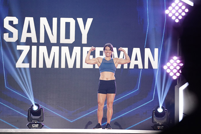Sandy Zimmerman posing on stage at American Ninja Warrior competition